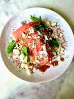 watermelon wedge salad with feta, mint leave and not just chili lime salad dressing on a a white plate